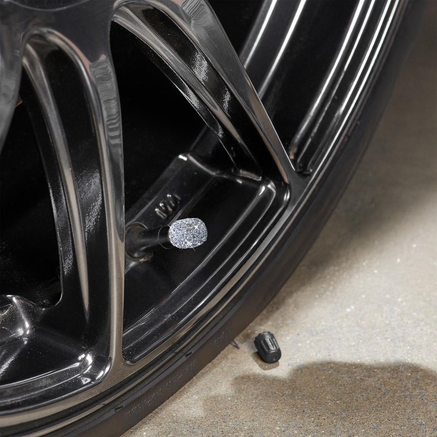 Close-up of rhinestone tire valve caps on black alloy wheel