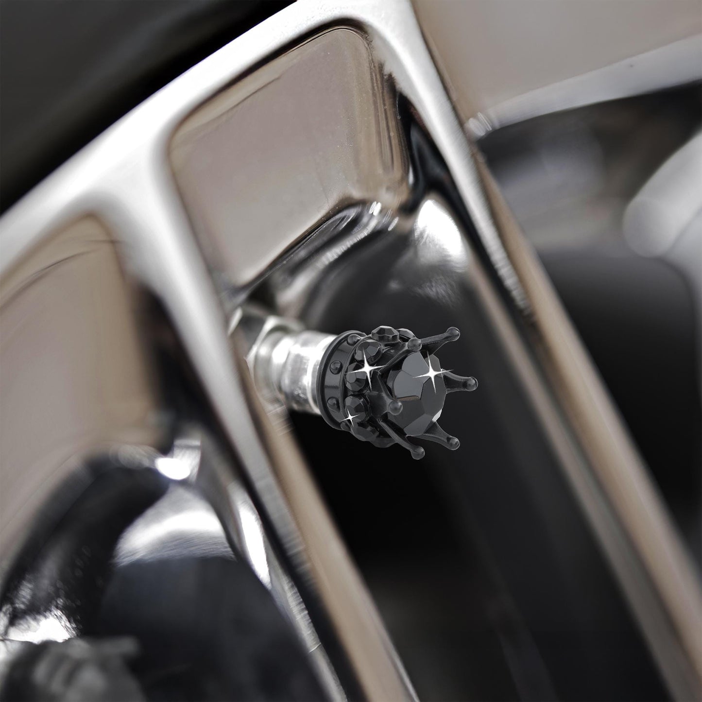 Black crown tire valve caps installed on alloy wheel close-up

