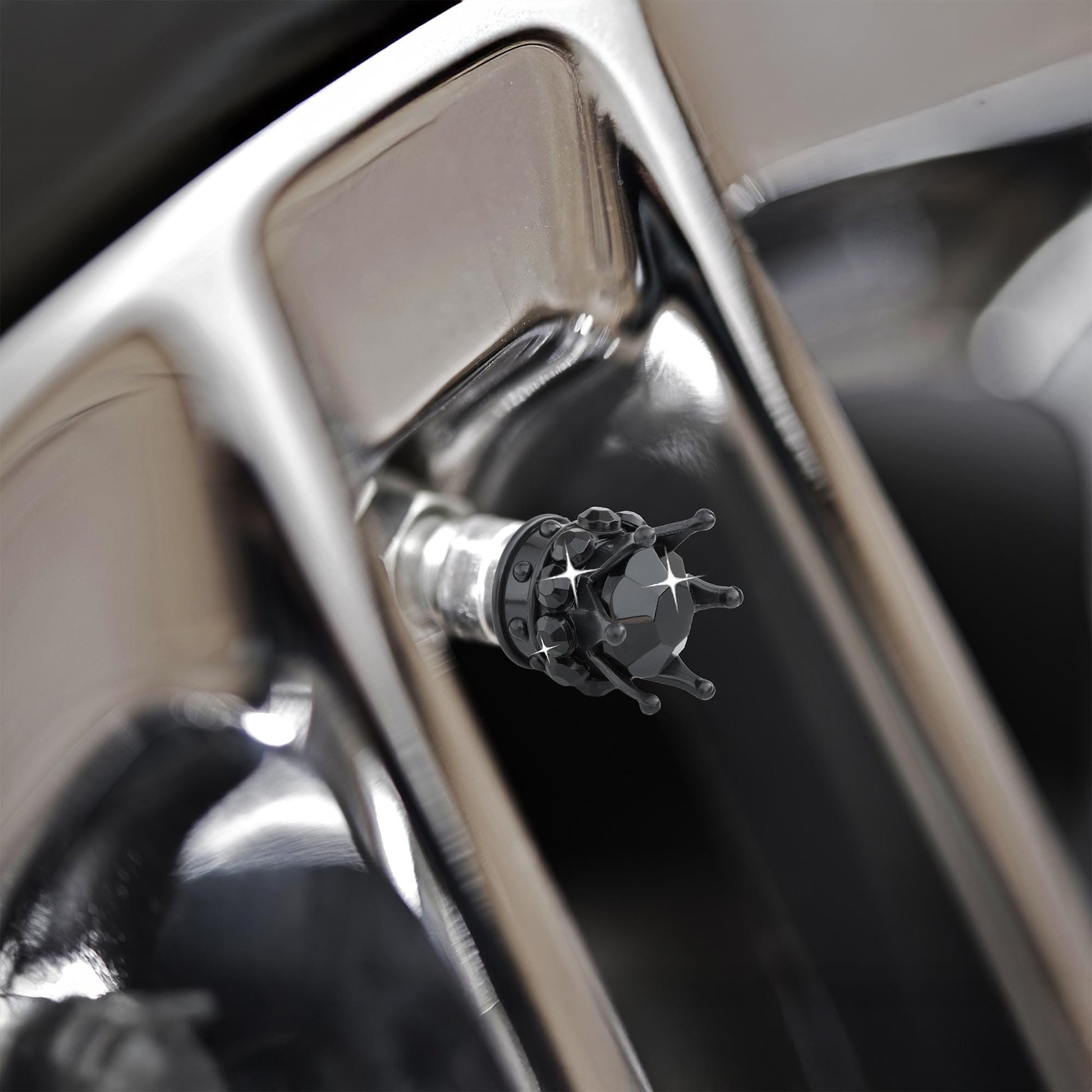 Black crown tire valve caps installed on alloy wheel close-up
