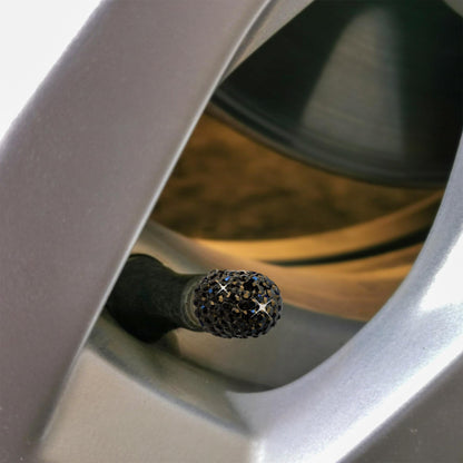 Black rhinestone tire valve caps installed on alloy wheel close-up
