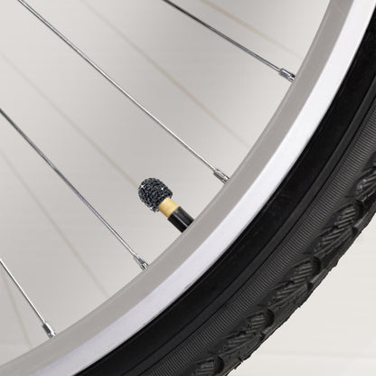 Black rhinestone tire valve caps on bicycle wheel close-up
