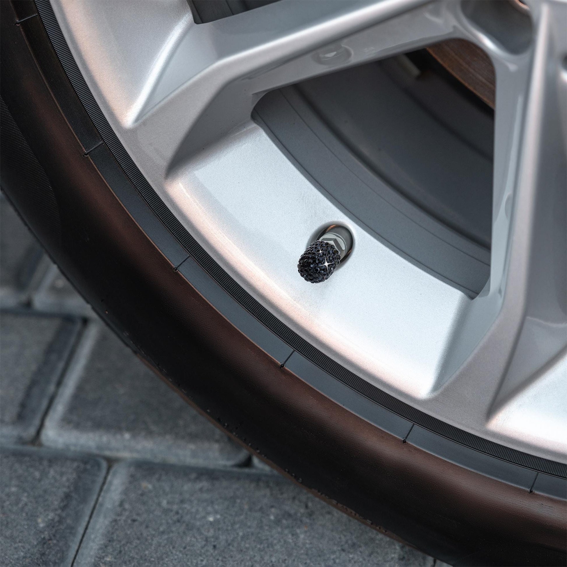 Black rhinestone tire valve caps installed on car wheel
