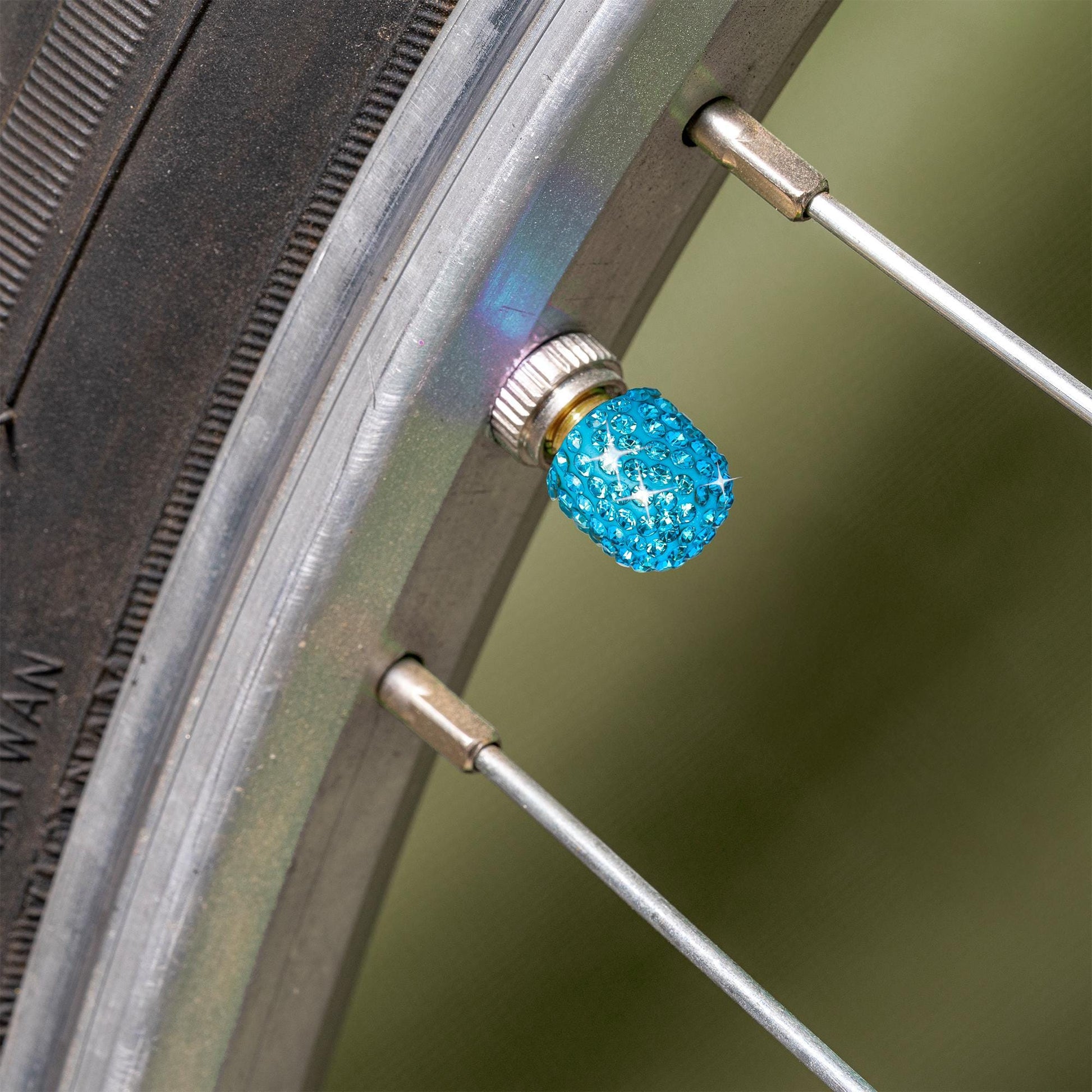 Blue rhinestone tire valve caps installed on bicycle tire valve stem
