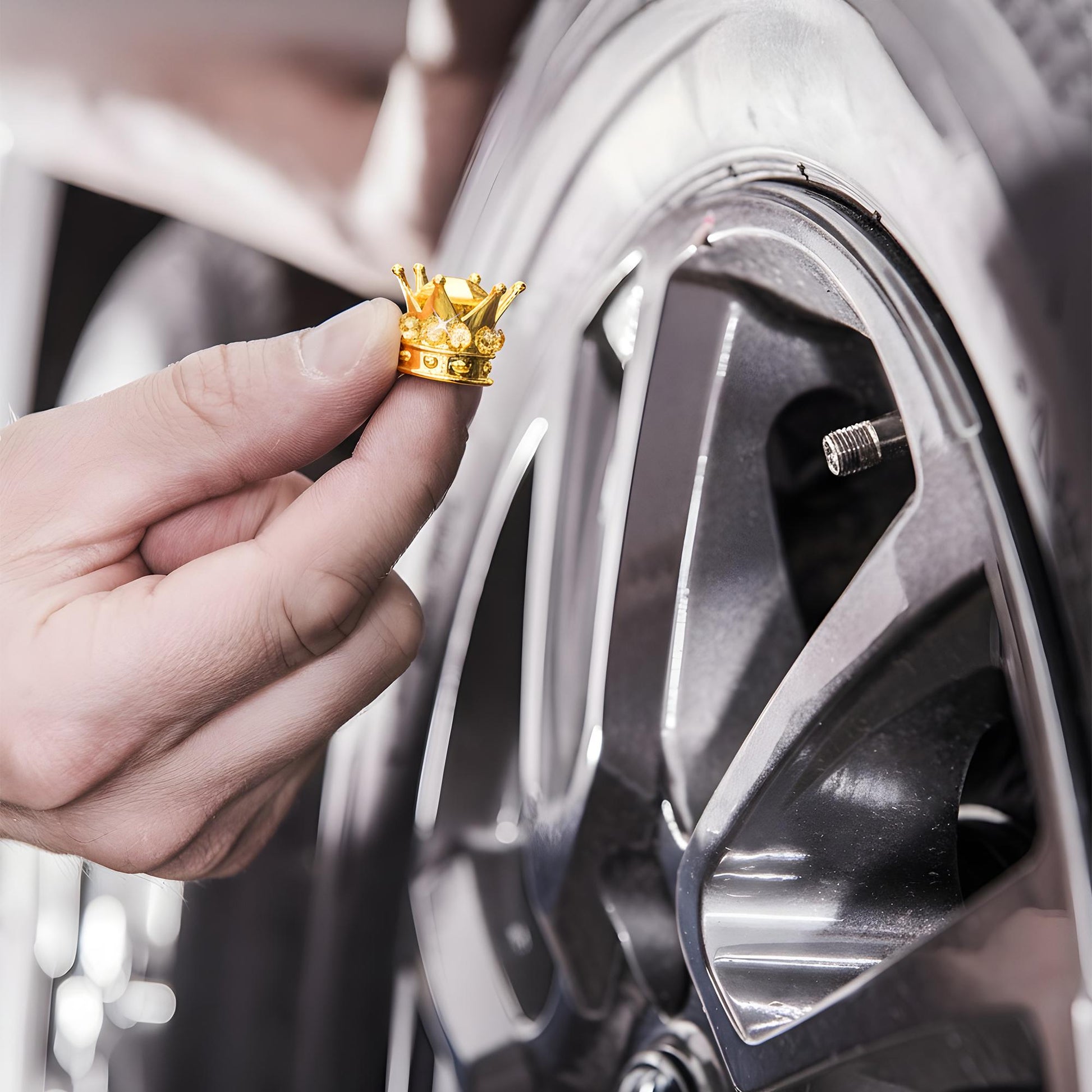 Hand installing gold crown tire valve caps on car wheel
