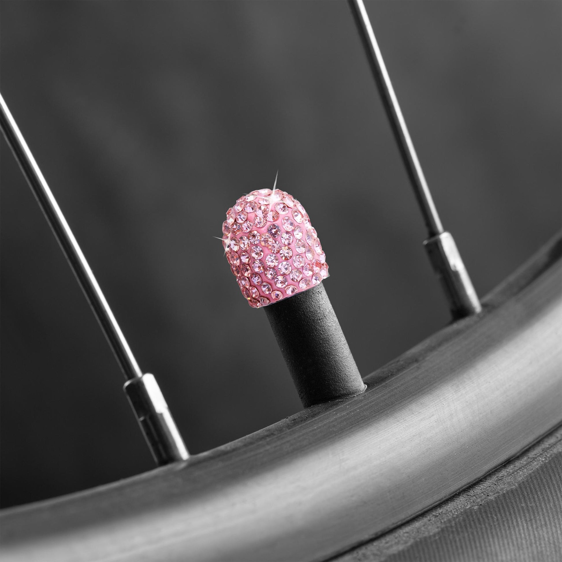 Pink rhinestone tire valve caps installed on bicycle tire valve stem
