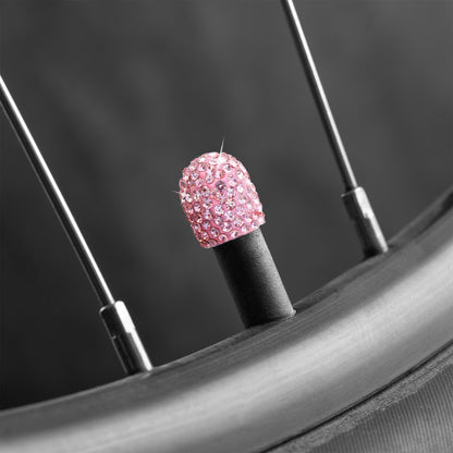 Pink rhinestone tire valve caps installed on bicycle tire valve stem

