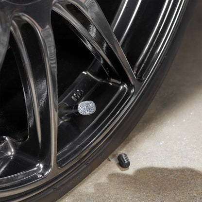 Close-up of rhinestone tire valve caps on black alloy wheel