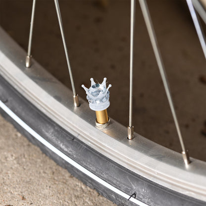 White crown tire valve caps installed on bicycle tire valve stem
